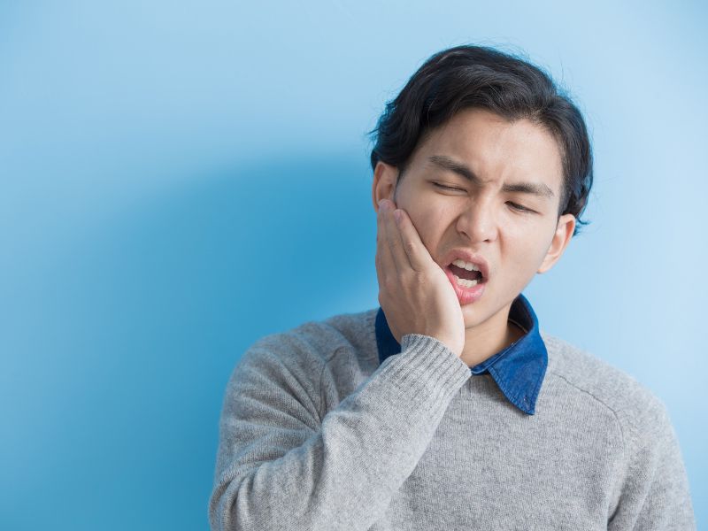 hombre con la mano en la mejilla, dolor de muela. endodoncia