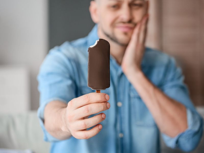 primer plano de helado de paleta y un hombre que lo sostiene y tiene dolor por sensibilidad dental. Endodoncia