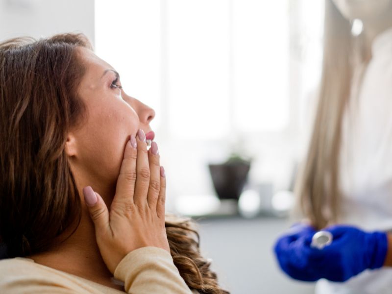 mujer en la urgencia dental con dolor en su mejilla